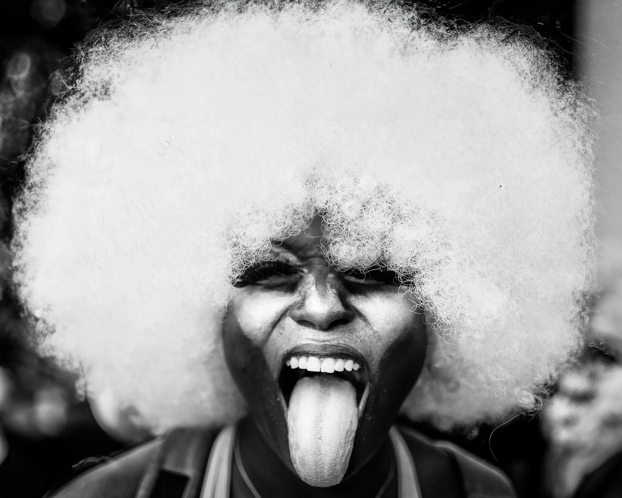 Woman with a white afro, mid-laugh
